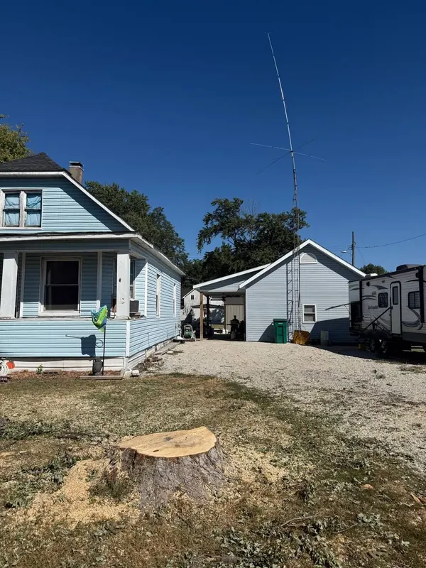 Freshly cut stump with sawdust beside a blue house after a tree removal
